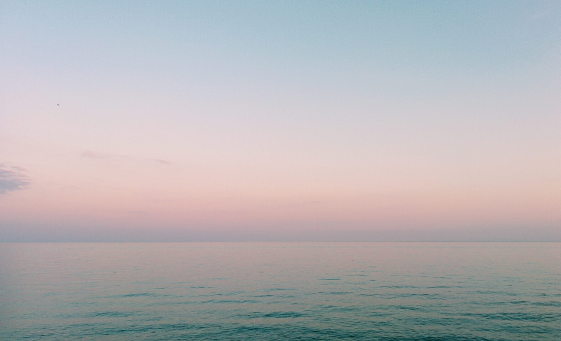 Calm sea horizon under a pastel sunrise.