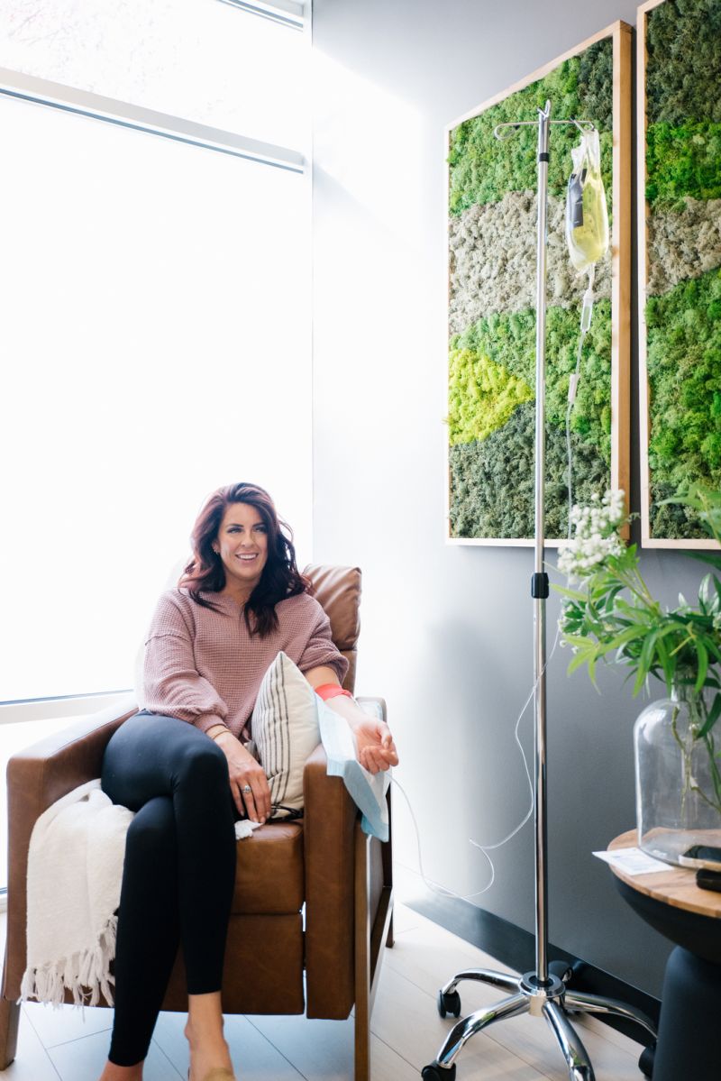 Woman smiling with IV drip in a modern clinic